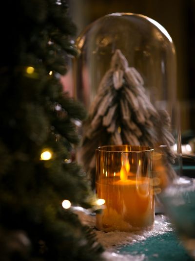 Lit candle with cozy decor and holiday vibes.