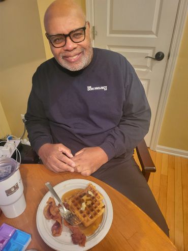 A man enjoying his bacon and pancakes dish