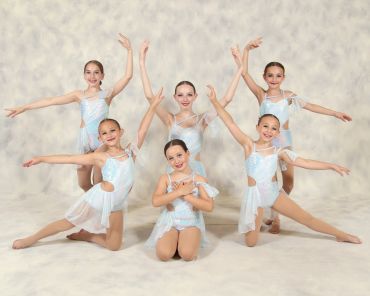 Six young ballet dancers posing in light blue costumes.