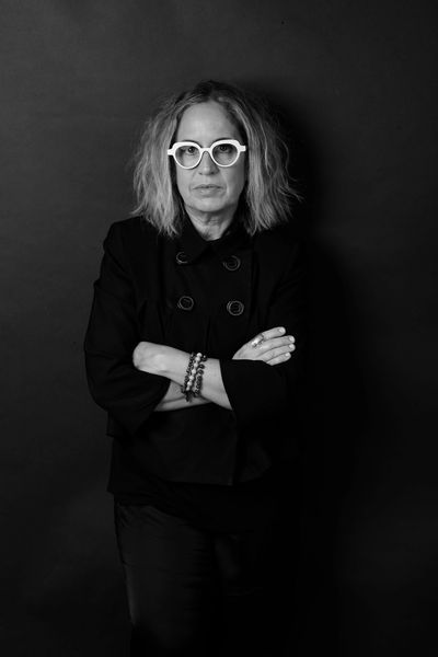 Woman with glasses and crossed arms in black-and-white photo.