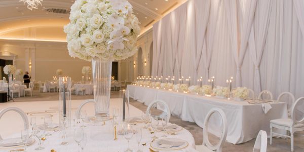 Elegant white floral centerpiece and candles adorn a wedding reception table.