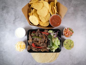 Mexican fajita meal with chips, salsa, and sides.
