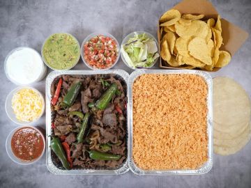 Mexican meal with beef, rice, chips, and sides.