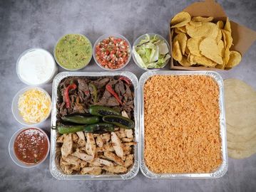 Mexican meal with chicken, steak, rice, chips, and various sides.