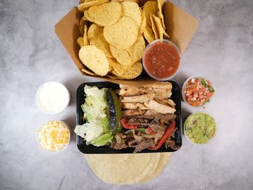 Mexican meal with grilled meats, chips, and dips.