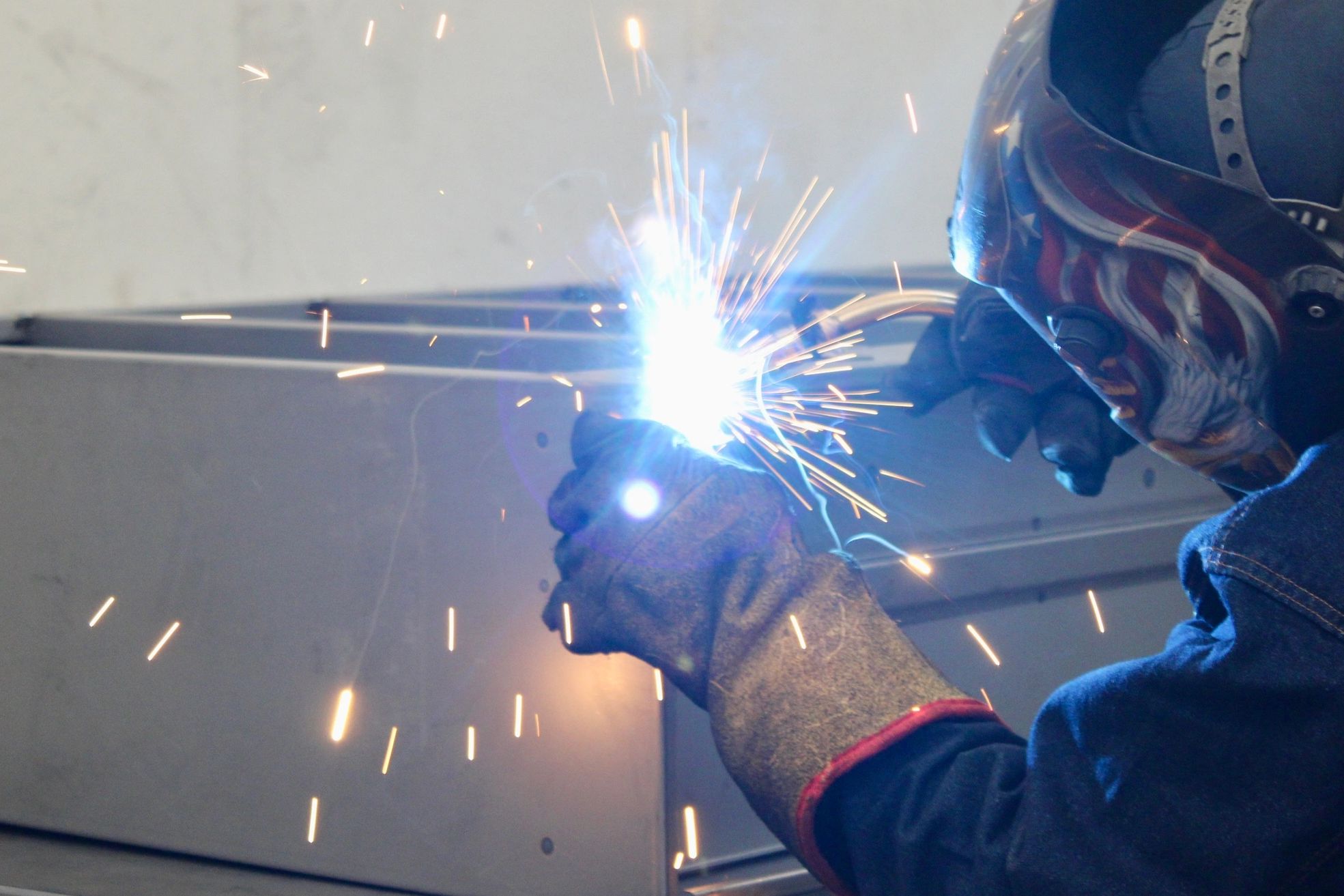 A welder in protective gear working with sparks flying.