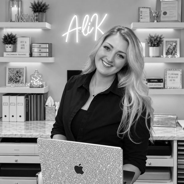 Smiling woman seated with a decorated laptop in a cozy office.