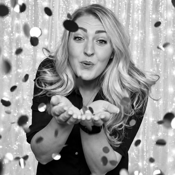 Woman blowing confetti towards the camera.
