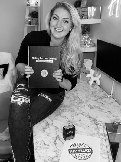 Woman holding a notary records journal, smiling.