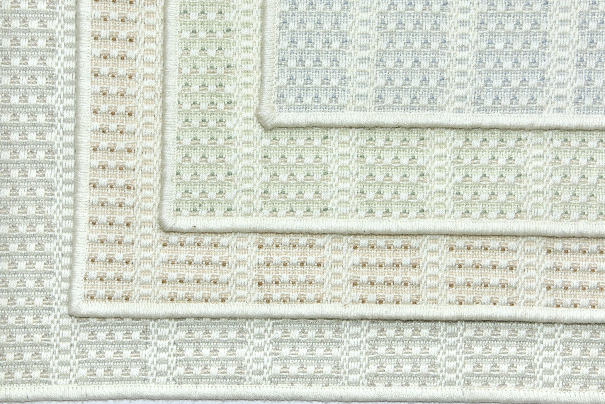 Stacked woven rugs with subtle geometric patterns.