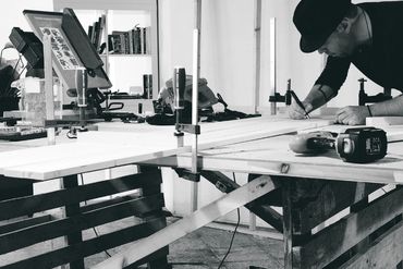 O artista Ada, Rob Adalierd trabalhando em uma mesa preparando um bastidor para pintura abstrata