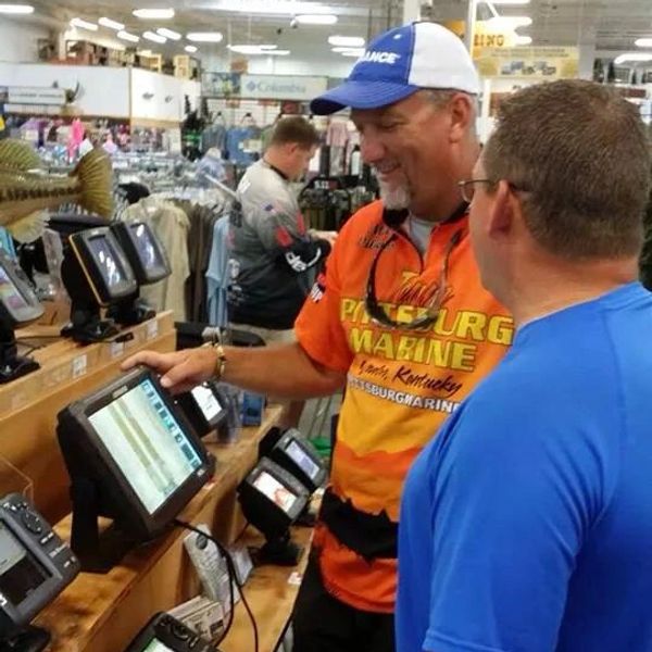 Two men examining fish finder devices in a store.