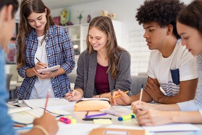 Group of teenagers working collaboratively around a table and smiling.