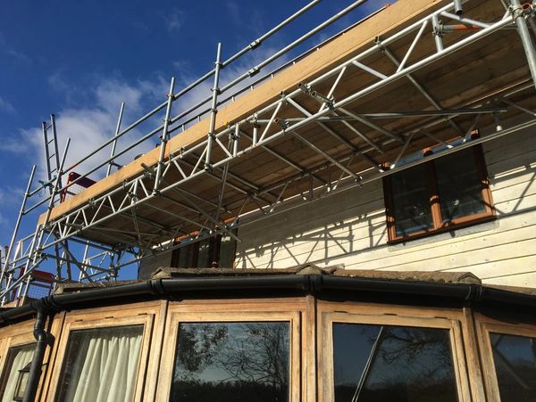 Scaffold beams over a conservatory to access a roof  for solar panel installation in bexhill, East S