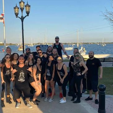 Group of friends posing by the waterfront with boats in the background.