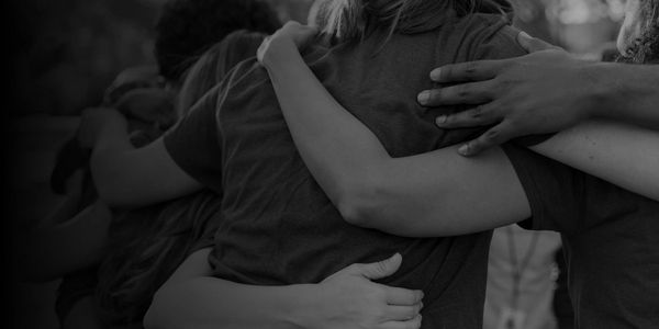 Group of people embracing each other in a supportive hug.