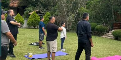 People standing outdoors on grass near yoga mats.