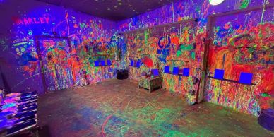 Vibrant neon paint splattered room under blacklight.
