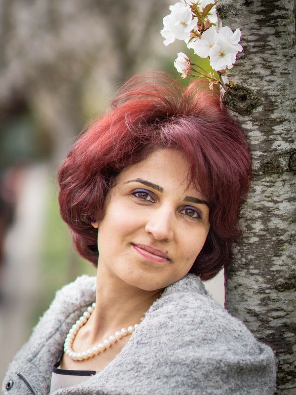 Leela Emadi certified counsellor, portrait near a tree with flowers