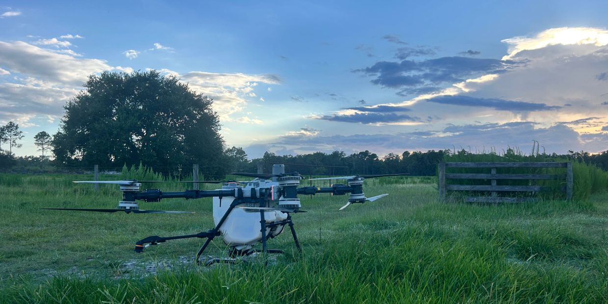 A large drone in a grassy field at dusk.