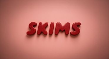 Red letters spelling SKIMS on a pink background.