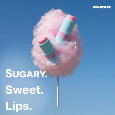 Lip balms nestled in pink cotton candy against a blue sky backdrop.