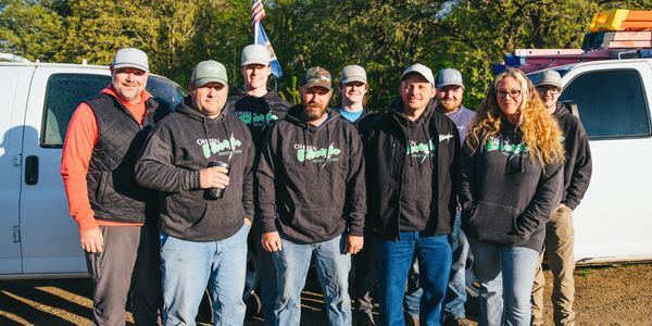 A group of workers posing outdoors in front of white trucks.