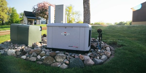 A Briggs &amp; Stratton generator outside on a rock bed in a yard.