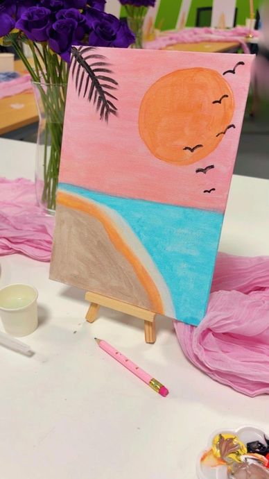Painting of a sunset beach scene on an easel.