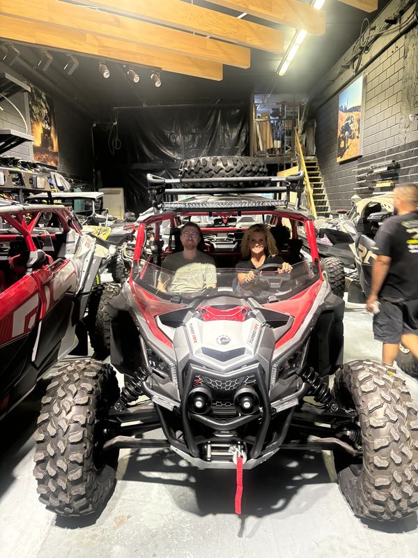 Two people inside an off-road vehicle in a garage.
