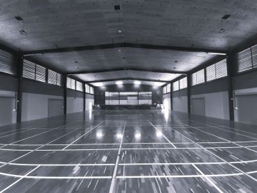 Empty indoor badminton court with polished wooden floor.