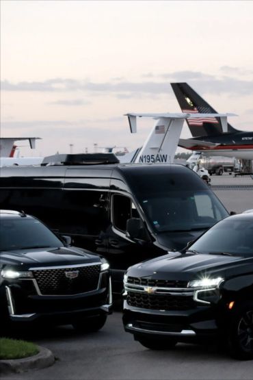 Luxury black vehicles parked near private jets.