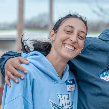 Smiling woman in a blue hoodie with a 'Hello' name tag.