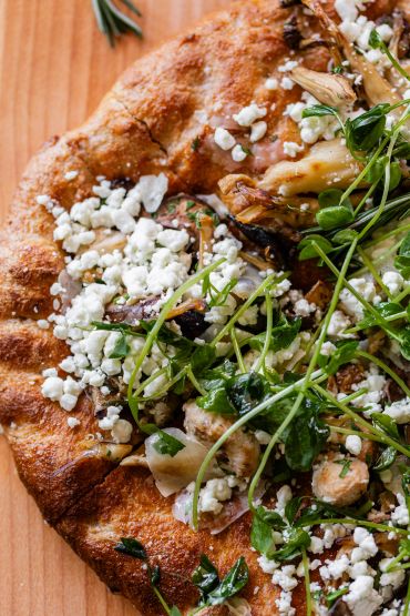 Close-up of a veggie pizza with greens and cheese.