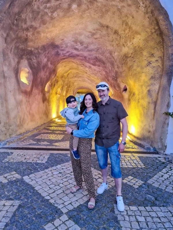 Family posing in a warmly lit tunnel with cobblestone floor.