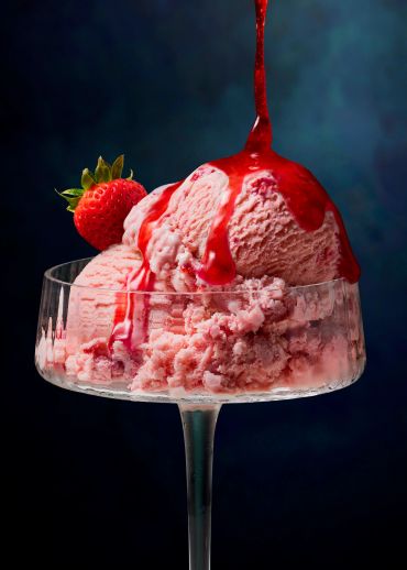 Strawberry ice cream with sauce in a glass.