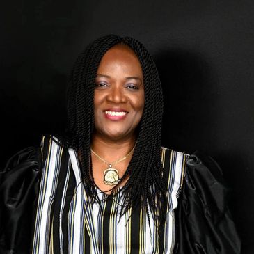 Smiling woman with braided hair in striped blouse against black background.