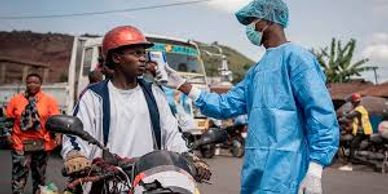 Healthcare worker checks temperature of a motorcyclist outdoors.