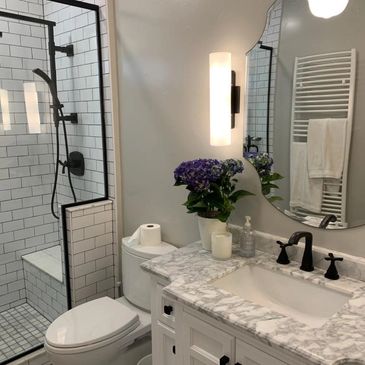 Remodeled bathroom with tile shower, floors, marble vanity, and wall hangings, black white and grey 