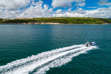 RIB in blue sea in Falmouth Bay with wake