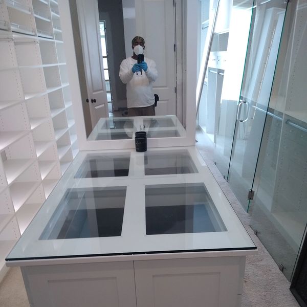 A person in protective gear takes a mirror selfie in a spacious, white walk-in closet.