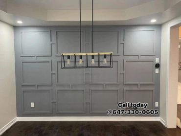 Modern dining room with gray paneled wall and hanging light fixture.