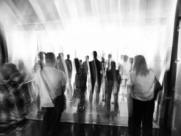 Blurry crowd walking through a bright corridor.