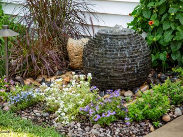 Outdoor garden with a stone water fountain and flowers.
