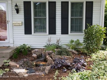 Front garden with a small rock waterfall and plants.