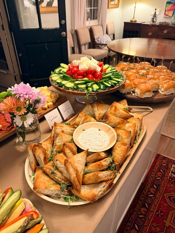 A table set with various appetizers including stuffed pastries, sliders, and fresh vegetables.