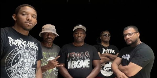 Five men posing together against a black background.