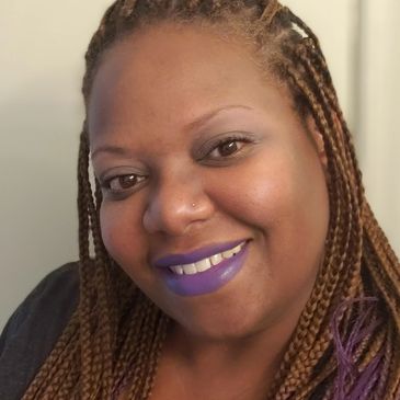 Close-up of a smiling woman with braided hair and purple lipstick.