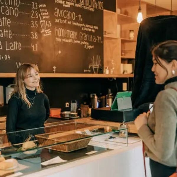 A friendly barista serving a customer at a cozy coffee shop counter.