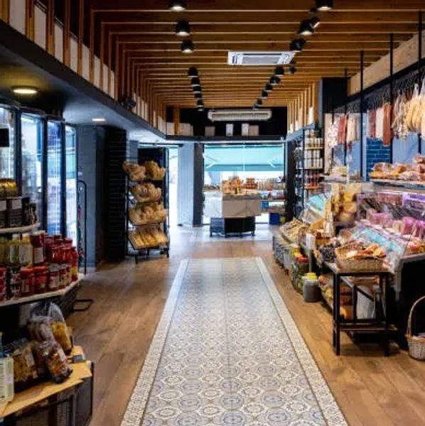 Modern gourmet grocery store aisle with wooden ceiling beams and neatly arranged products.
